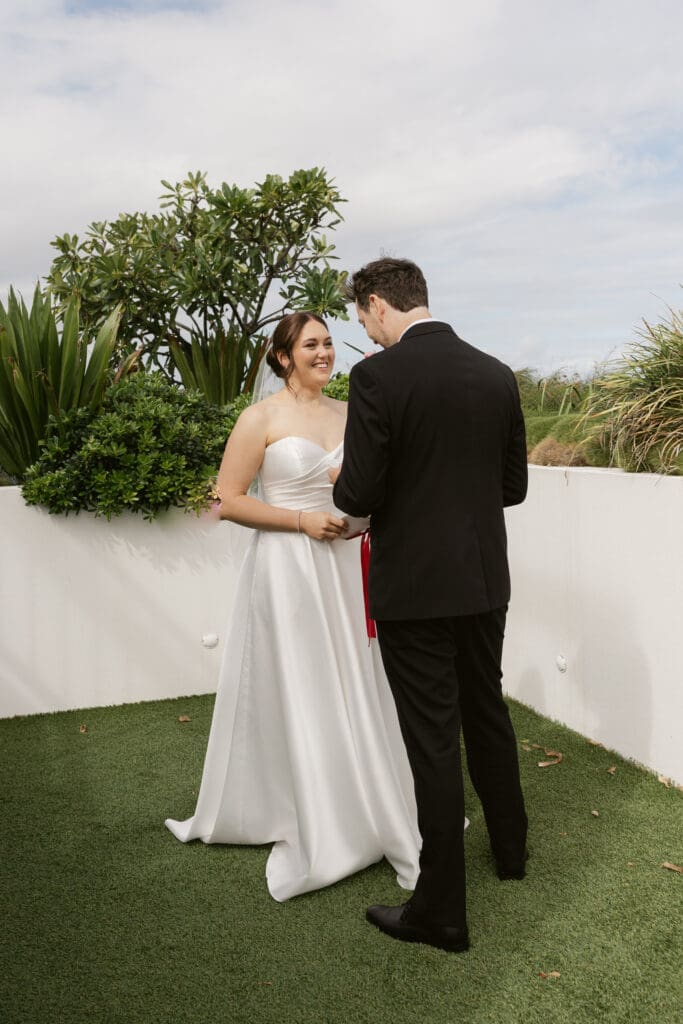 Couple standing together during an intimate outdoor wedding ceremony in a modern landscaped venue with natural greenery.